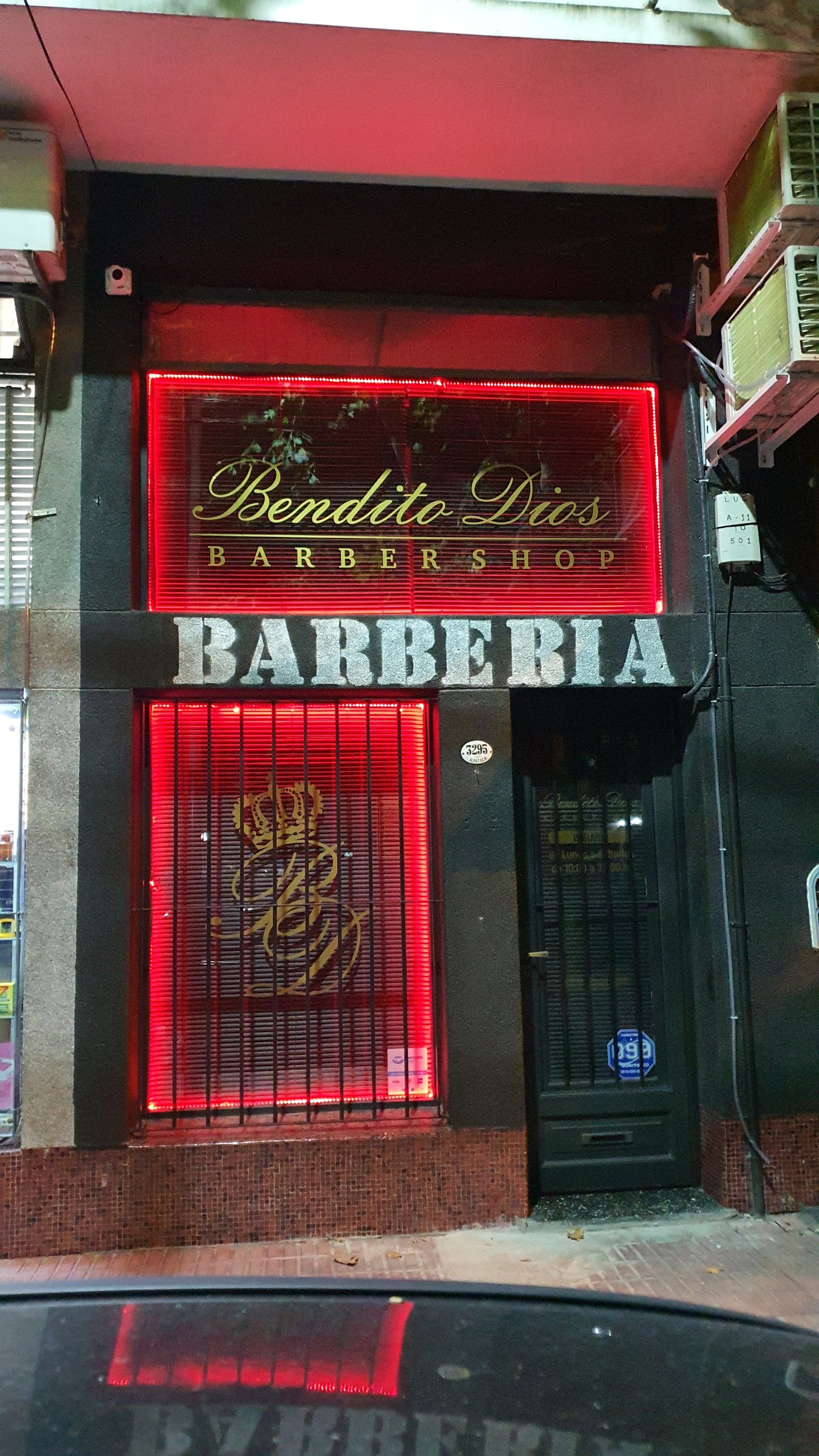 Fachada de Bendito Dios Barbershop de noche